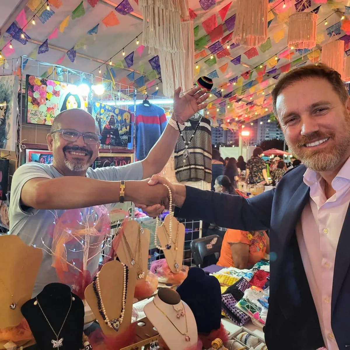Héctor De Castro shaking hands with a local artisan at a community market in Mexico