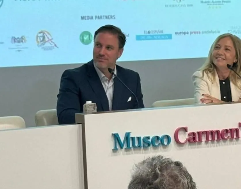 Héctor De Castro seated at a speakers’ table at the Museo Carmen Thyssen in Málaga, beside a fellow speaker