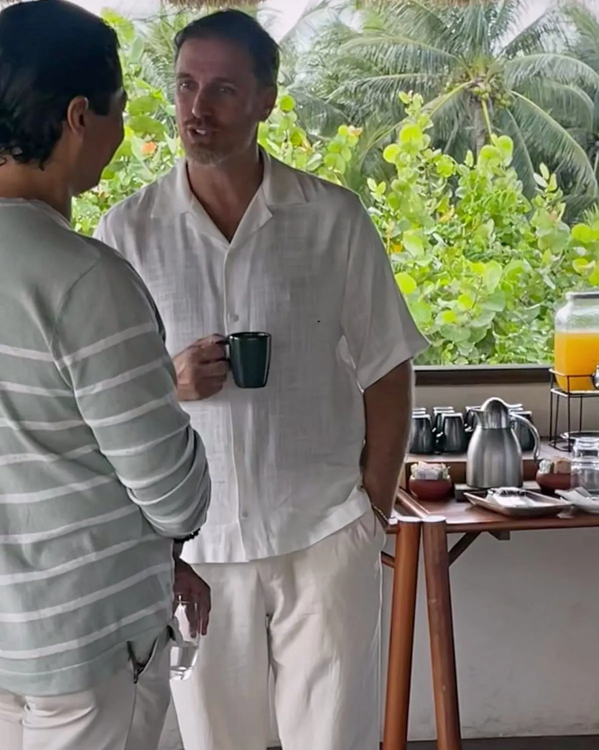Héctor De Castro in conversation on a terrace overlooking tropical vegetation