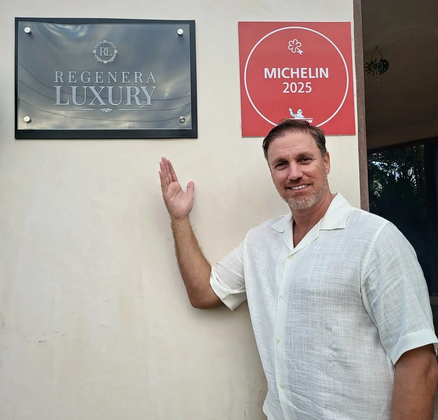 Héctor De Castro beside a Regenera Luxury plaque and a MICHELIN 2025 sign on a hotel wall